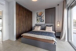 Ein modernes Schlafzimmer mit einem großen Bett, einem Holzschrank, einem Gemälde und einem Fenster.