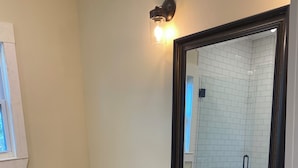 Uma casa de banho com sanita branca, uma pia com espelho em cima e um armário com gavetas.