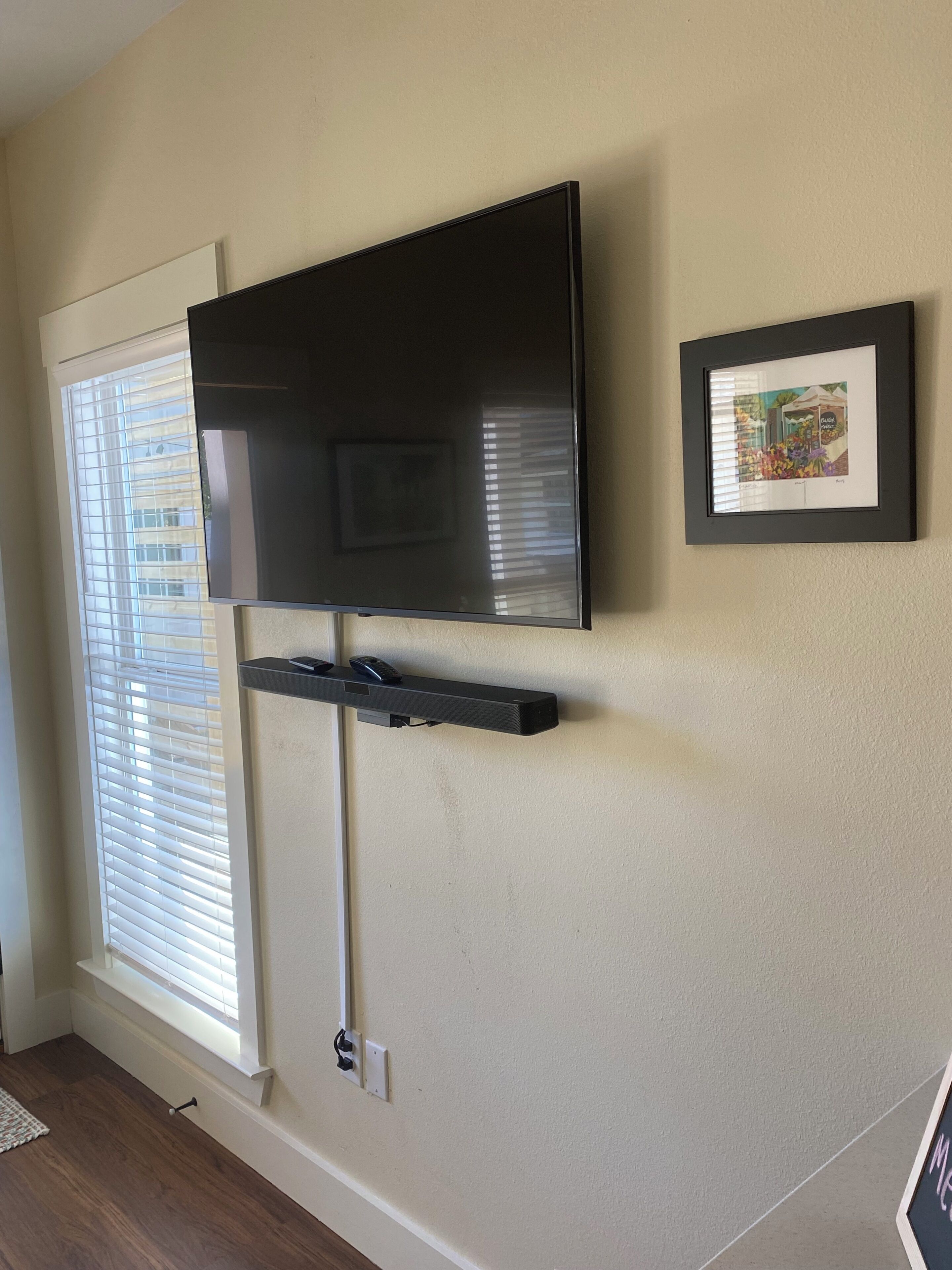 Een flatscreen-tv aan een muur bevestigd, met een fotolijst aan de rechterkant.