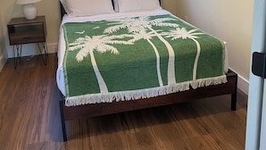 Quarto com cama, duas janelas, mesa de cabeceira, luminária e ventilador de teto.