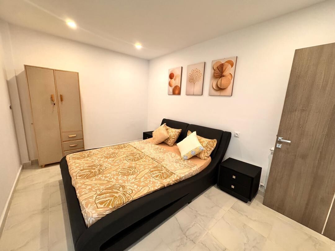 Une chambre à coucher comprenant un lit, des tables de chevet, une armoire et des œuvres d’art murales.