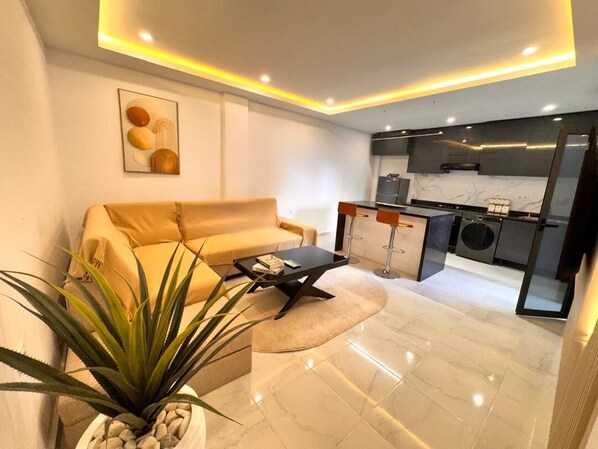 A modern living room with a sofa, coffee table, and a potted plant. - 🌟 Luxury & Designer 2-Bedroom Apartment — Millennium Boulevard, Oran (Oran)