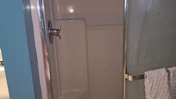 A bathroom with a shower enclosure, a towel rack with a towel, and a toilet.