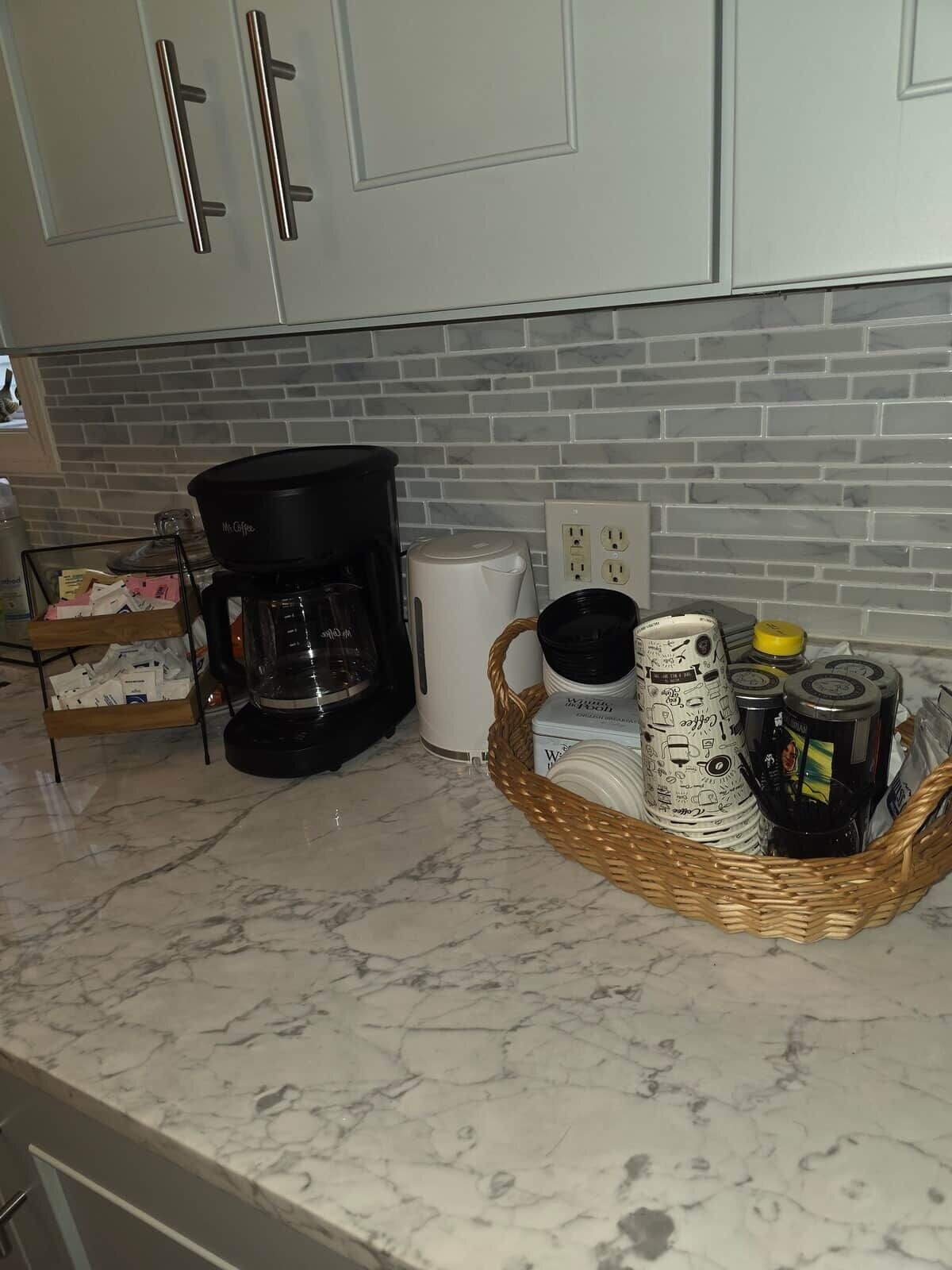 Eine Küche mit Marmorarbeitsplatten, einer Kaffeemaschine, einem Toaster und einer Sammlung von Tassen.