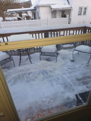 A window with a metal grill and a view of a snowy street. - Cozy 2 Bedroom Suite walking distance to downtown (Rutland)