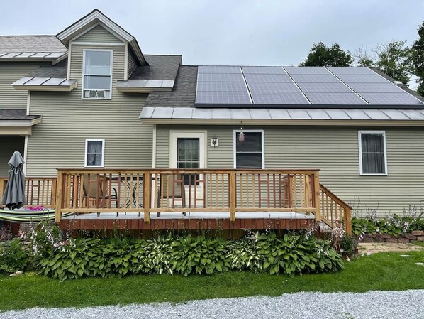 A house with a wooden deck, solar panels, and a well-maintained garden.