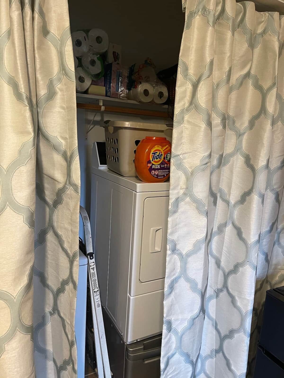 A laundry room with a washing machine, a basket, and a detergent bottle.