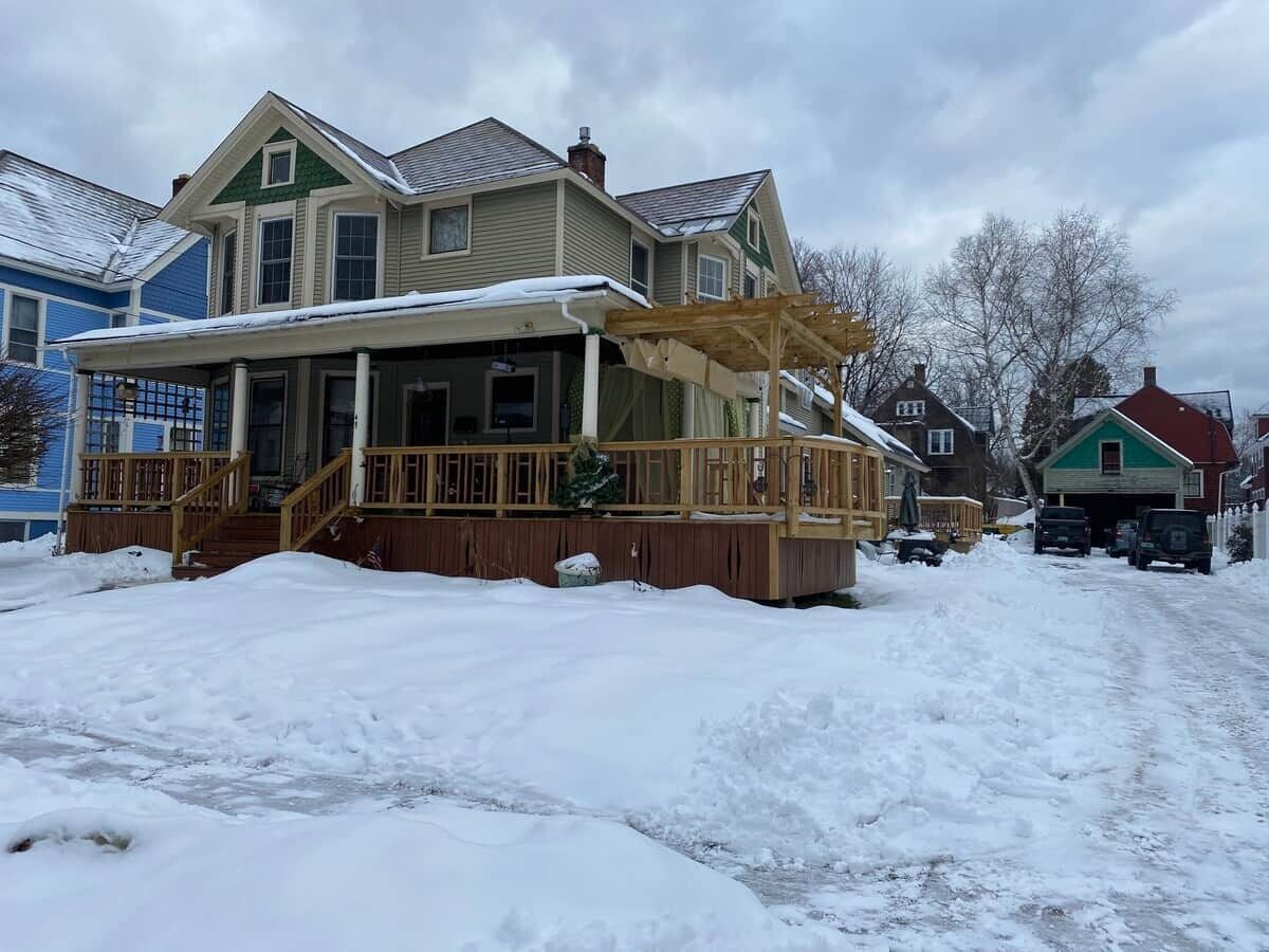 A two-story house with a covered porch and a snow-covered driveway.
