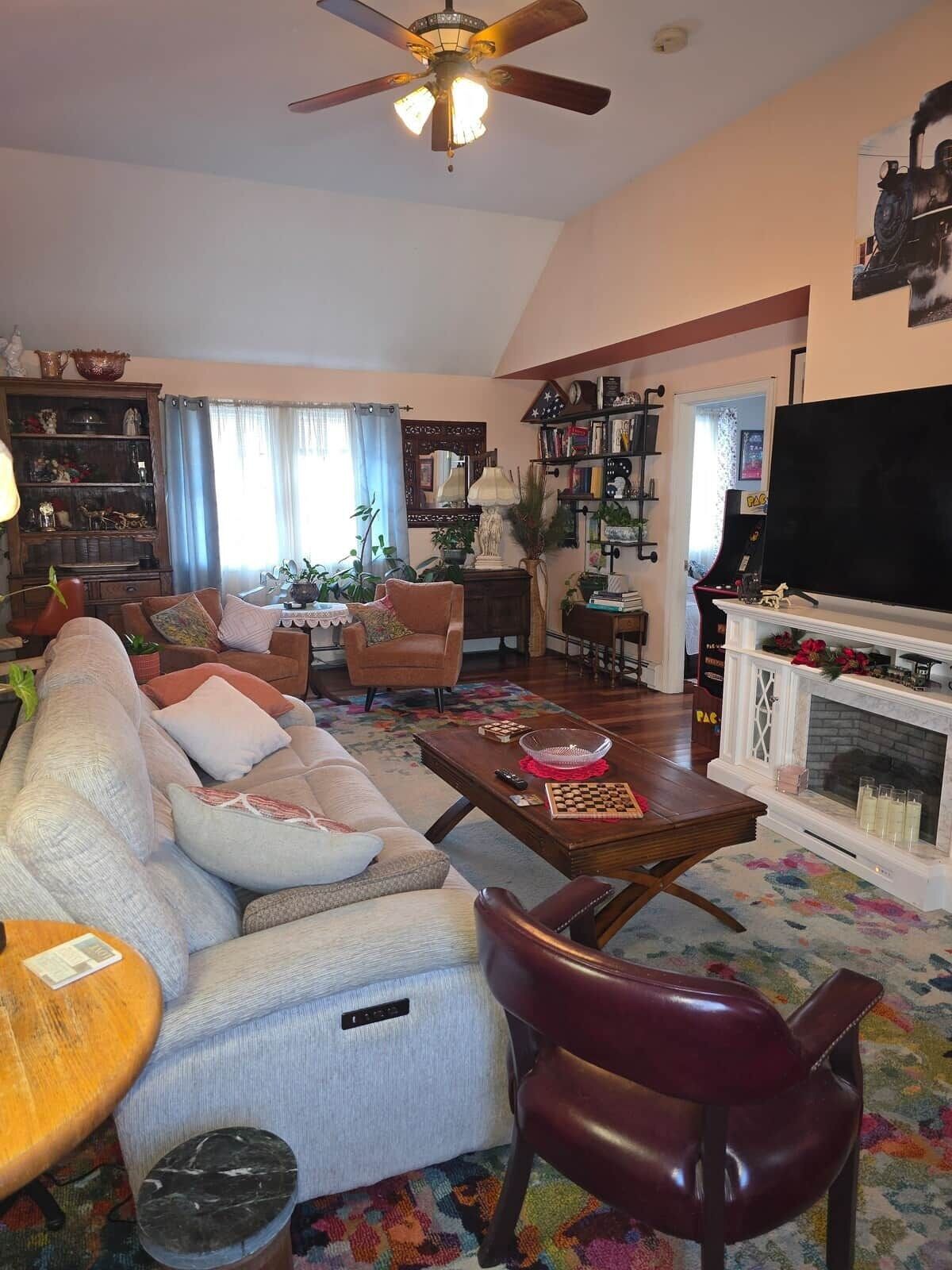 Una sala de estar con sofá, sillones, una mesa de centro, chimenea, televisor y estantería.