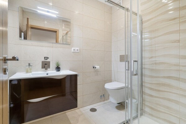 A modern bathroom with a glass shower enclosure, a dark brown vanity, and a white toilet.