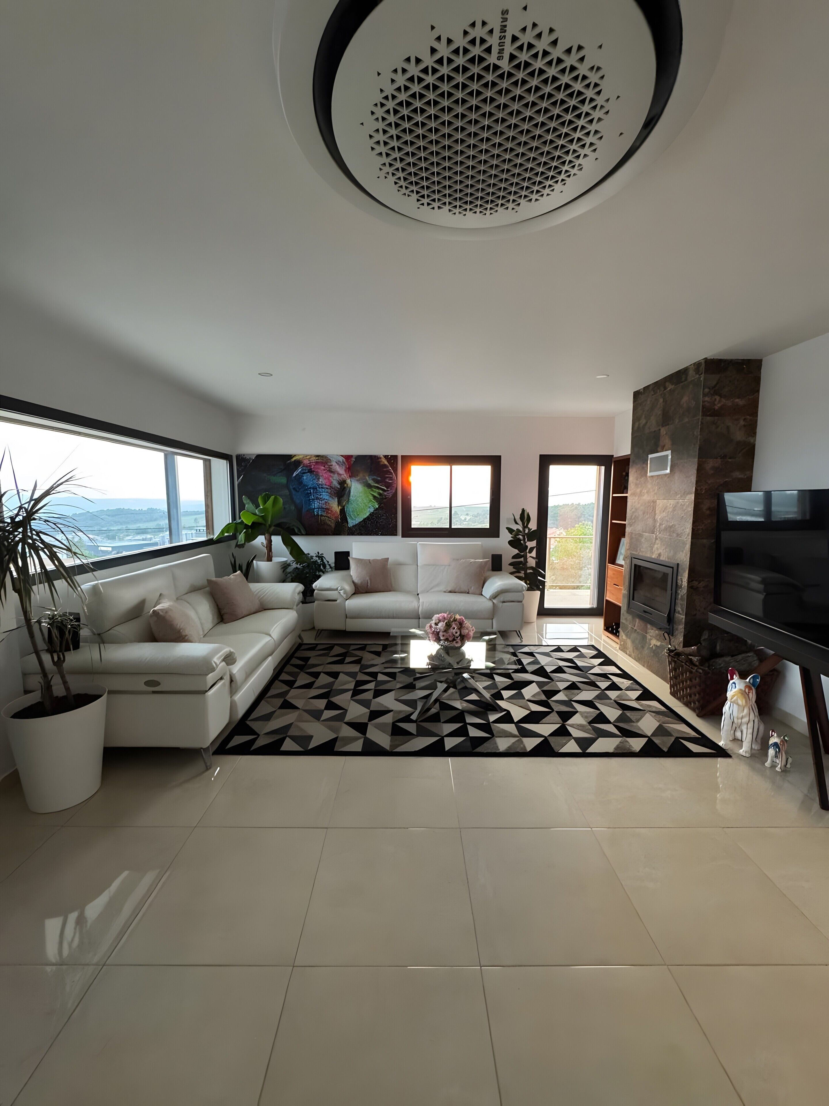 A modern living room with a sofa, a coffee table, a fireplace, and a television.