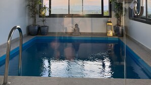 Una piscina con vistas a la puesta de sol a través de un ventanal amplio.