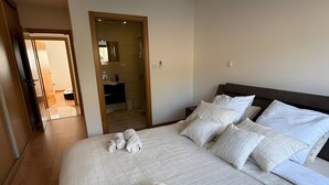 Habitación de hotel con una cama grande, un baño visible a través de una puerta abierta y suelo de madera.