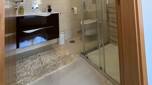 Un baño moderno con cabina de ducha de vidrio, tocador con espejo y un inodoro.