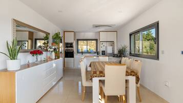Una cocina y comedor moderna con armarios blancos, una isla central con plantas y una mesa de comedor lista para cuatro.