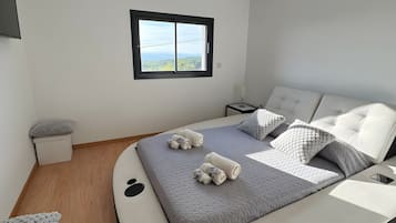 Un dormitorio moderno con una cama curva, vistas a través de una ventana y una mesita de noche.