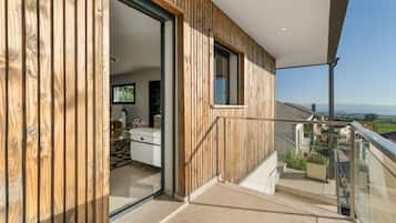 Un interior moderno con revestimiento de madera, un balcón con barandilla de vidrio y vistas al campo.