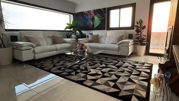 Una sala moderna con un sofá modular, una mesa de centro con flores y una alfombra geométrica.