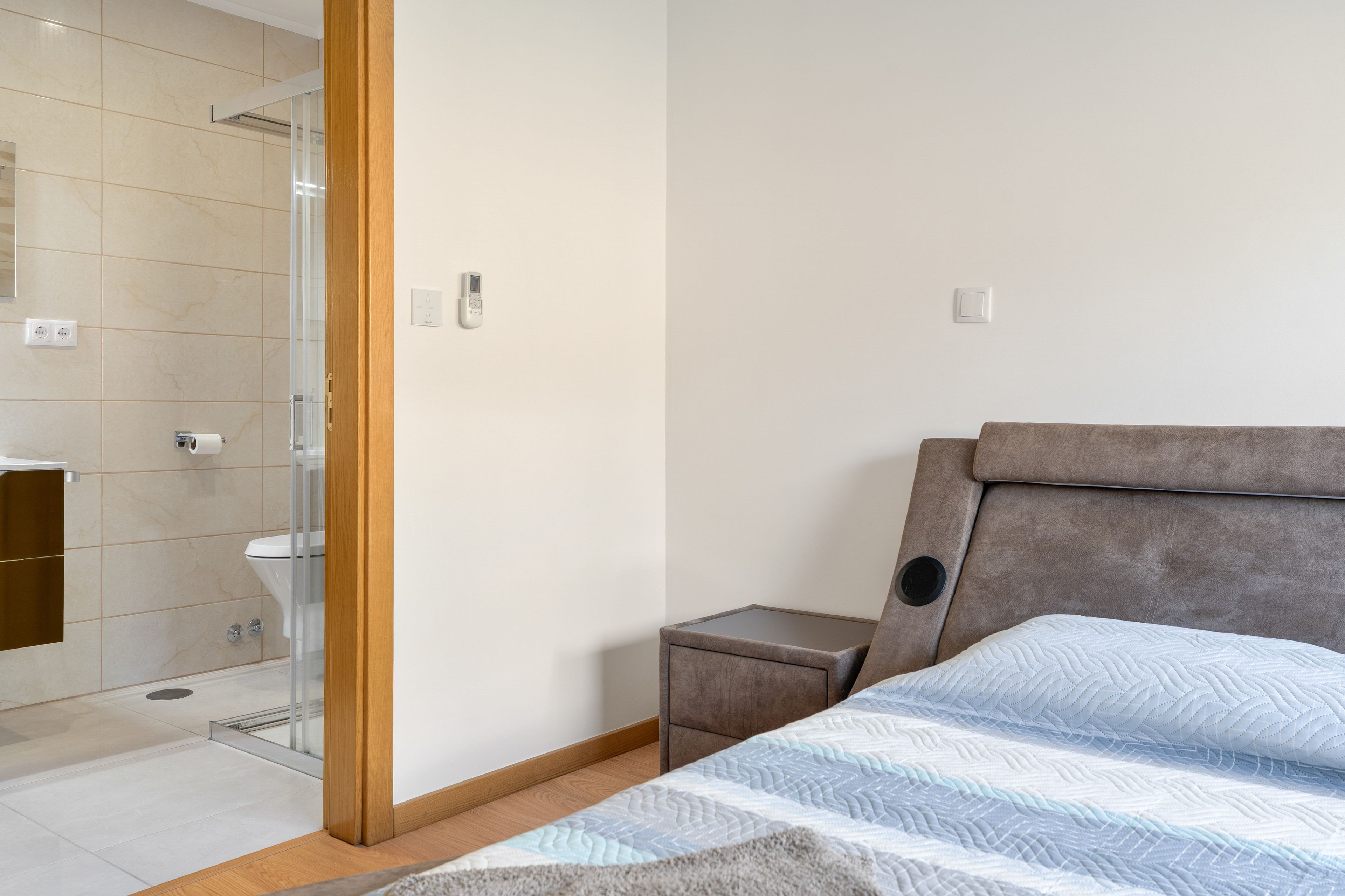 Une chambre à coucher comprenant un lit, une table de chevet, une commode, des toilettes et un espace douche.