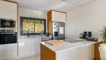 A modern kitchen with white cabinetry, a built-in oven, a refrigerator, and a coffee maker.