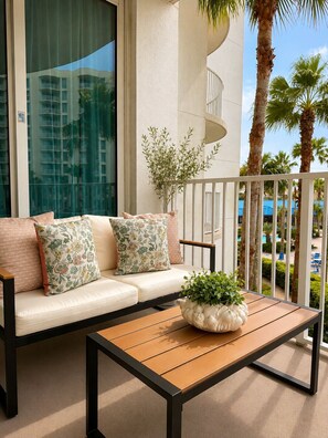 A balcony with a sofa, a table, and a potted plant. - Cozy Coastal Escape, Resort Pool + Walk to Beach (Destin)