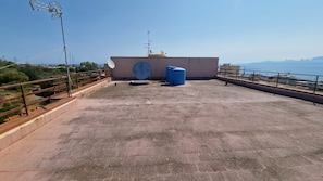Una terrazza sul tetto con un'antenna parabolica, un serbatoio d'acqua e vista sul mare.