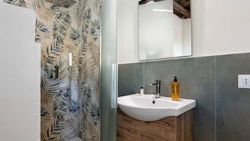 Une salle de bain avec une douche, un lavabo et un miroir.