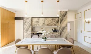 A modern dining area with a marble table, chairs, and pendant lighting. - A PEACEFUL & REFINED RETREAT IN THE HEART OF THE RIVE GAUCHE – RUE DU BAC (Paris)