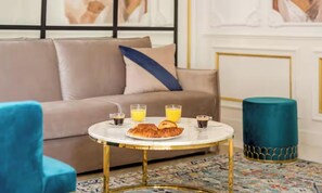 A room with a sofa, a round coffee table with breakfast items, and a patterned rug. - A PEACEFUL & REFINED RETREAT IN THE HEART OF THE RIVE GAUCHE – RUE DU BAC (Paris)