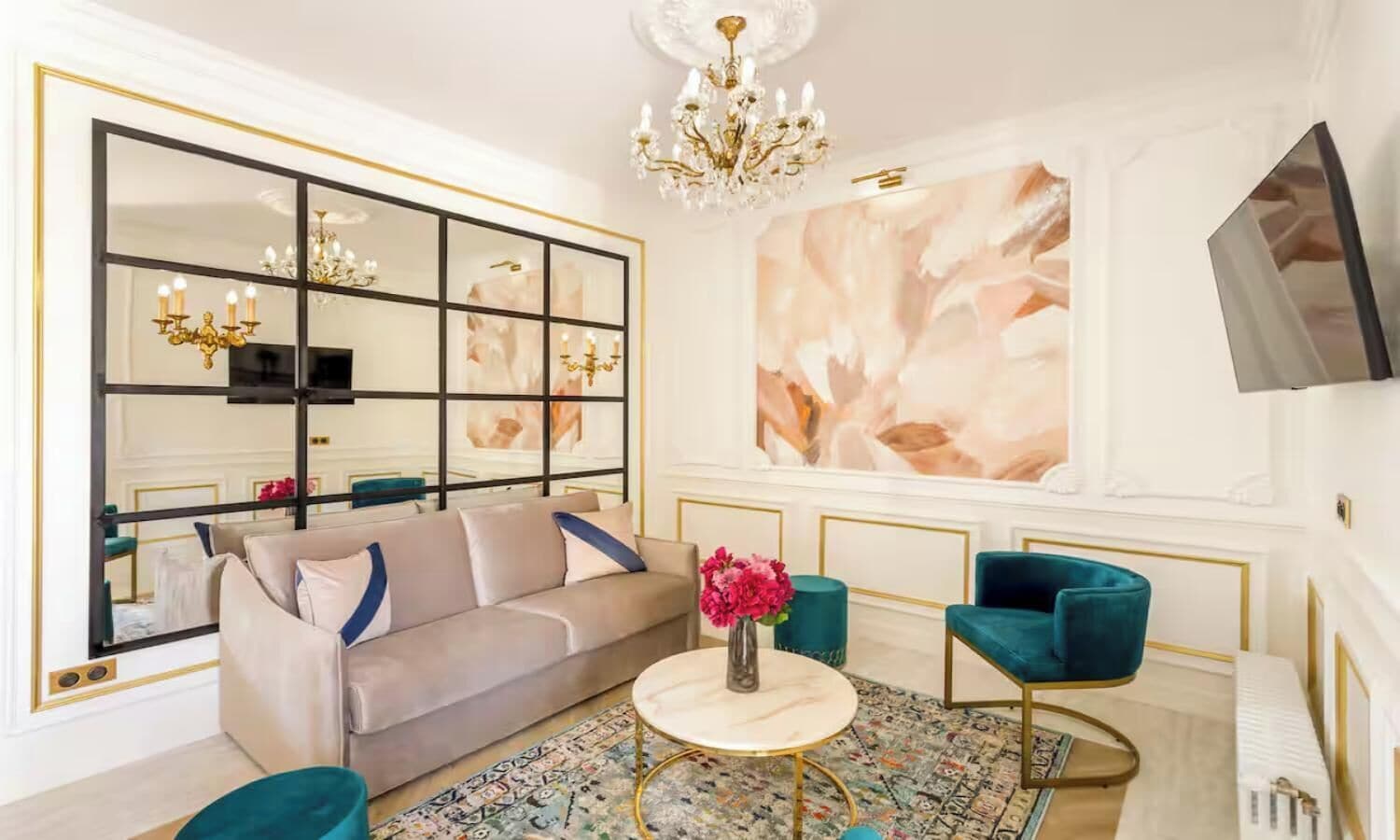 A modern living room with a sofa, two armchairs, a coffee table, and a large mirror with a gold frame.