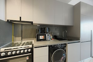 A compact kitchen with a built-in stove, microwave, and dishwasher. - Bloomfields Studio Mag Eye 910 - Meydan (Dubai)