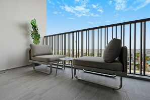 A balcony with two grey sofas, a small table, and a potted plant. - Bloomfields Studio Mag Eye 910 - Meydan (Dubai)