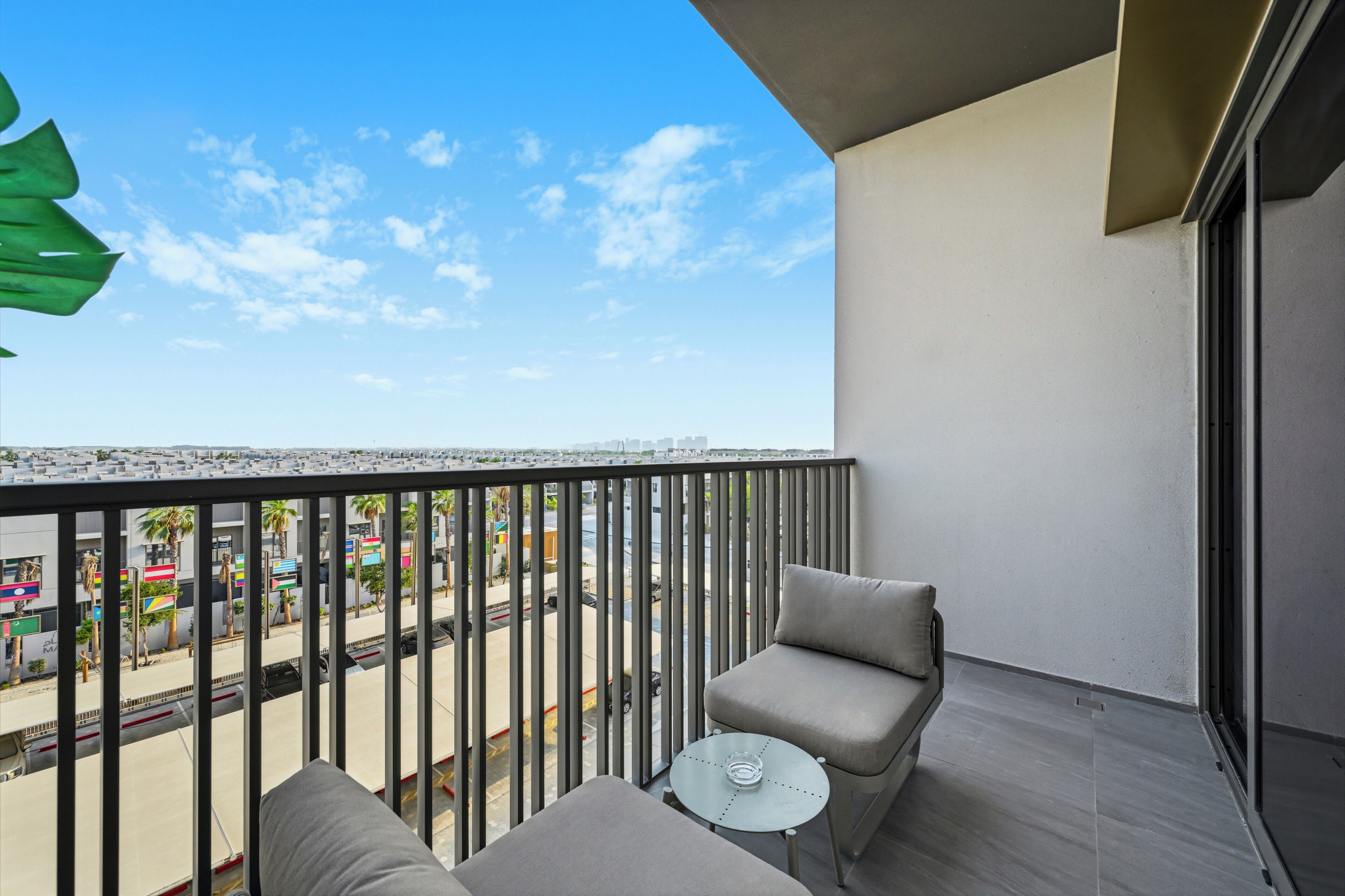A balcony with a view of a cityscape, a small table, and two chairs.