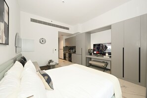 A modern hotel room with a large bed, a television, and a kitchenette. - Bloomfields Studio Mag Eye 910 - Meydan (Dubai)