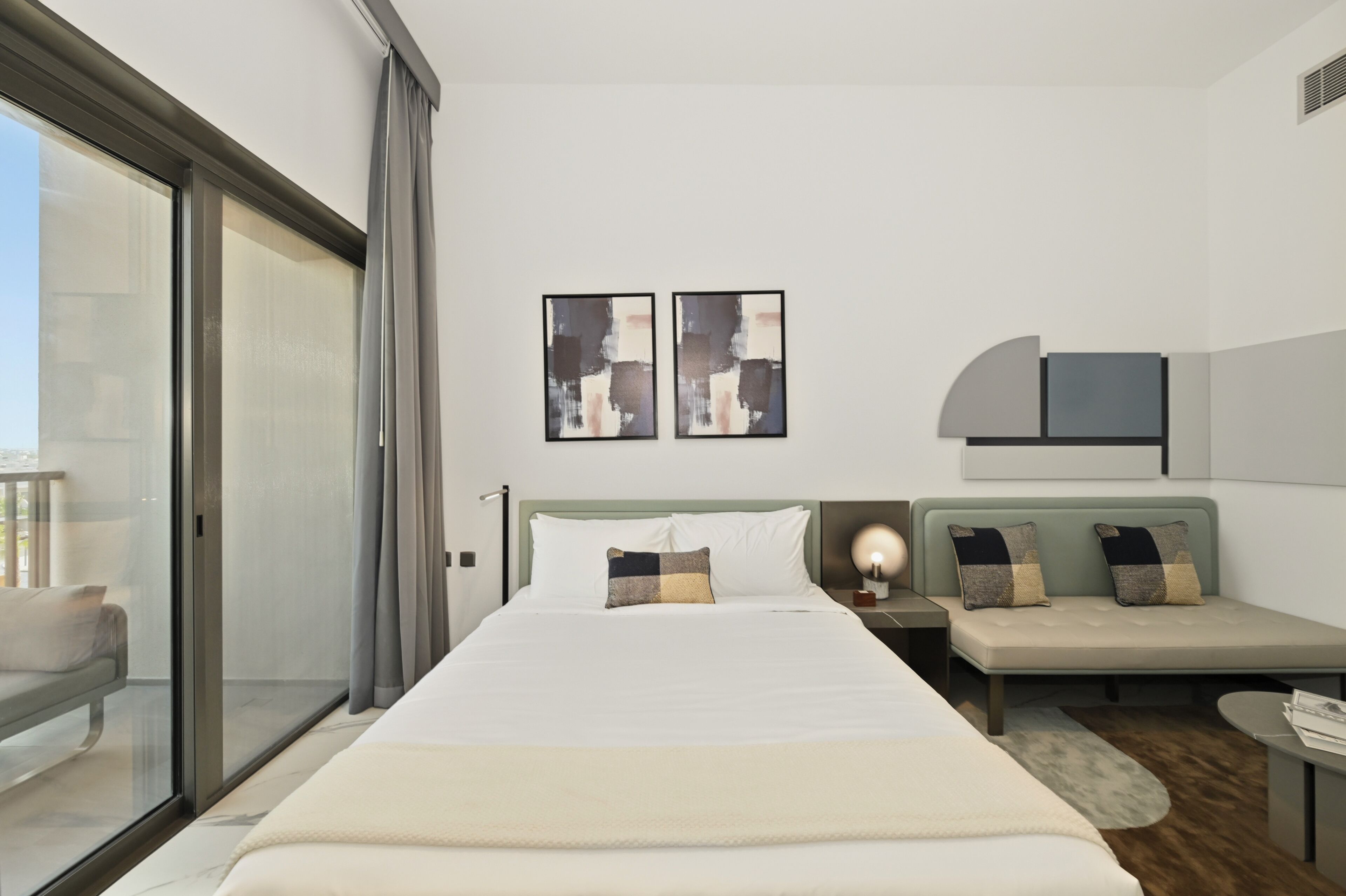 Una habitación de hotel moderna con una cama grande, zona de estar y balcón.