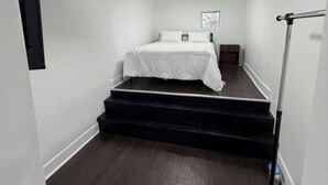 A bedroom with a bed, a window, and a staircase leading to an upper level. - 2-bedroom Bronzeville Gem (Chicago)