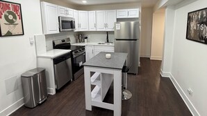 A modern kitchen with white cabinets, stainless steel appliances, and a central island. - 2-bedroom Bronzeville Gem (Chicago)