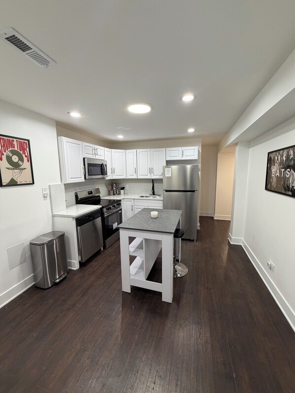 Una cocina moderna con gabinetes blancos, electrodomésticos de acero inoxidable y una isla central.