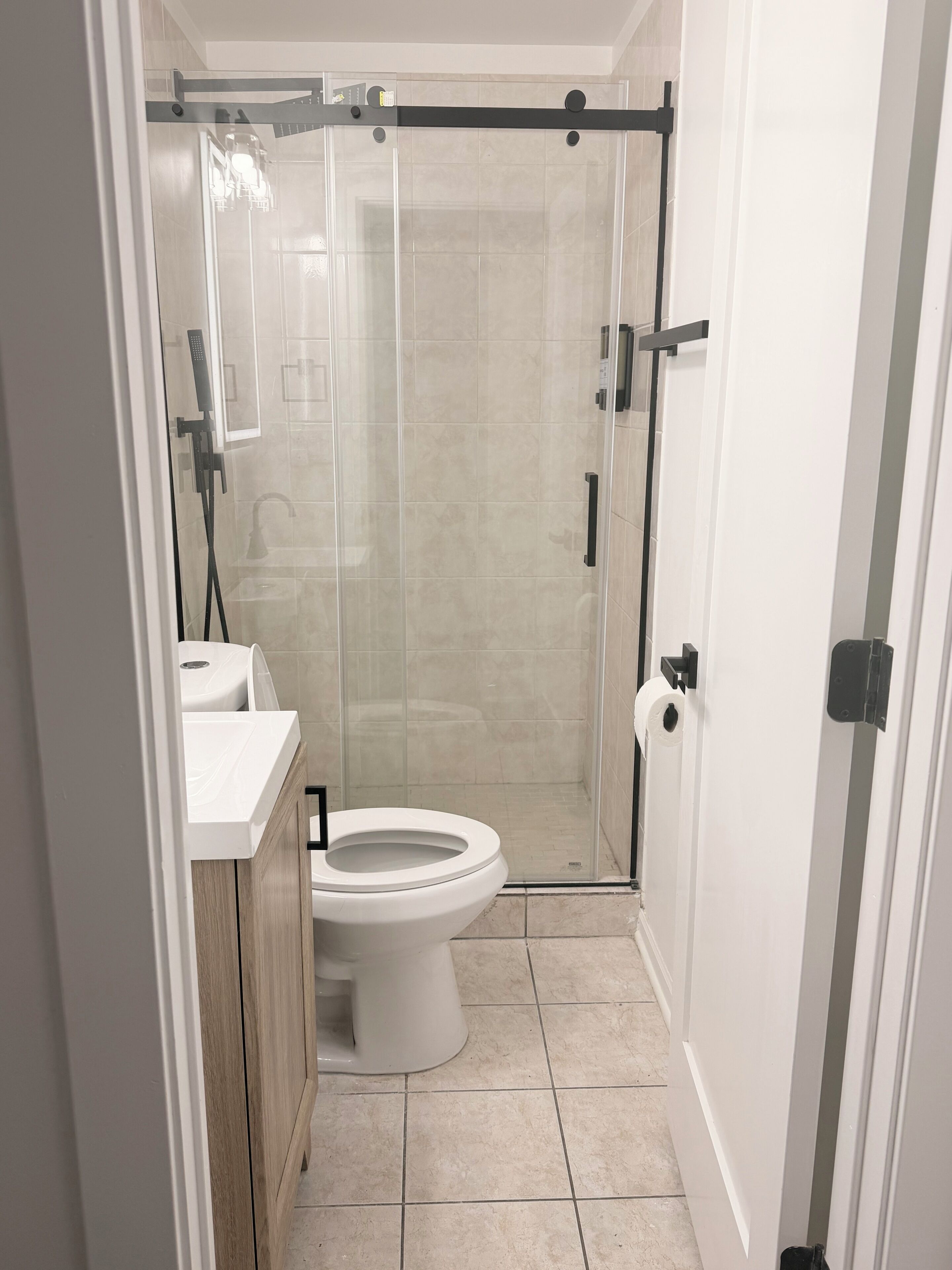 A modern bathroom with a toilet, sink, and shower enclosure.