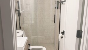 A modern bathroom with a toilet, sink, and shower enclosure. - 2-bedroom Bronzeville Gem (Chicago)
