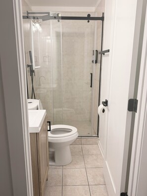 Een moderne badkamer met toilet, wastafel en douchecabine.