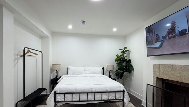 A modern bedroom with a bed, bedside tables, a hanging plant, and a fireplace. - 2-bedroom Bronzeville Gem (Chicago)