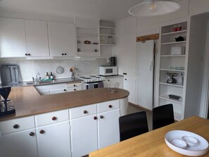 A modern kitchen with white cabinets, a wooden countertop, and a dining area with a table and chairs.