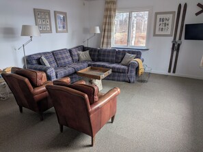 A living room with a sectional sofa, leather armchairs, a coffee table, and a window with a view of trees. - Spacious homes with river views (Ytterhogdal)