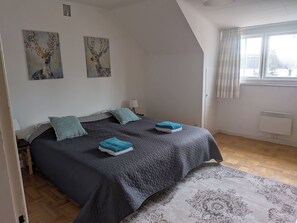 A bedroom with a bed, two pillows, a window, and two wall paintings. - Spacious homes with river views (Ytterhogdal)
