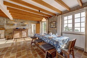 Un comedor rústico con pared de piedra, vigas de madera y un gran ventanal.