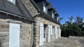 Ein Gebäude aus Stein mit zahlreichen Fenstern und Eingängen, einem gepflasterten Innenhof und blauem Himmel.