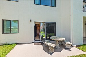 A building with a patio area featuring a table and two benches. - 🐾 Sunset Harbor Palms 2-102 | Pet Friendly Studio on Santa Rosa Sound (Navarre Beach)