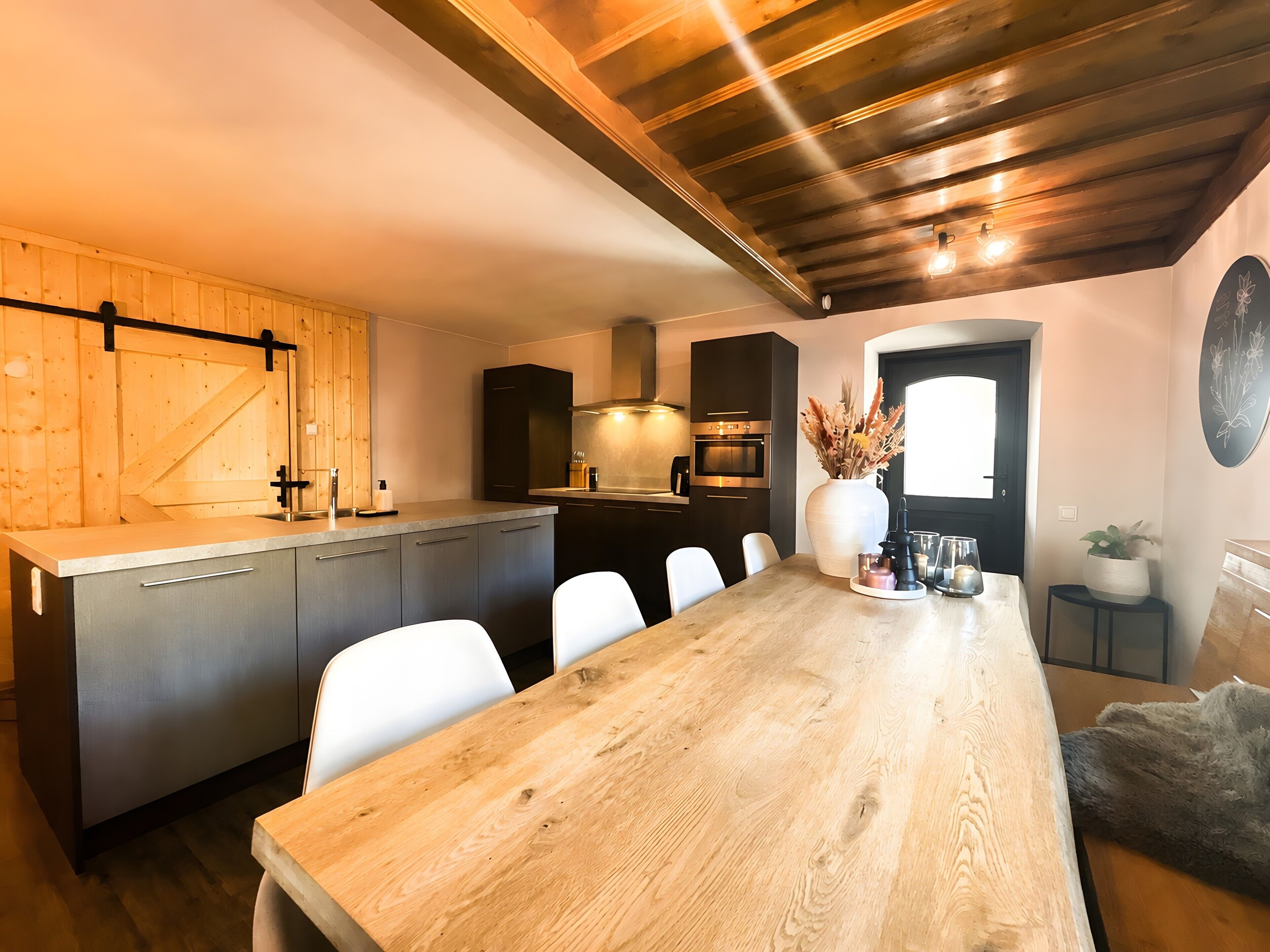 A modern kitchen with a wooden countertop, built-in appliances, and a dining area with a wooden table and chairs.