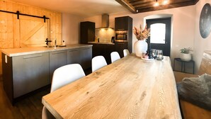 Una cocina moderna con encimera de madera, electrodomésticos integrados y una zona de comedor con mesa y sillas de madera.